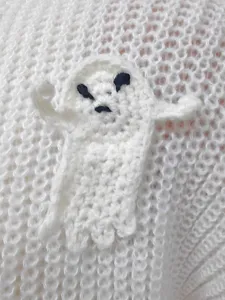 Dettaglio di maglione lavorato a maglia di Halloween con applicazione fantasma all'uncinetto.