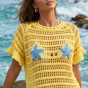 Detailed view of a yellow hollow-out knit beach cover-up with blue crochet starfish ornaments