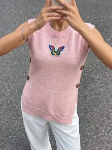 Detailansicht einer rosa Strickweste mit Pailletten-Schmetterling und Seitenknöpfen