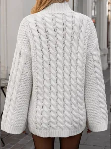 Detailansicht der Rückseite mit Zopfstrickmuster eines gemütlichen weißen Rollkragenpullovers.