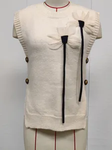 Close-up of off-white knitted sweater vest with 3D flower appliqué and side buttons