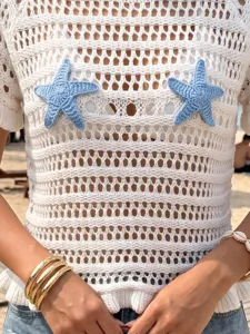 Detailed view of blue starfish appliques on white crochet knit beach cover-up