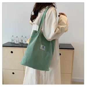 Elegante bolso de pana verde llevado por una modelo en un ambiente de estilo zen