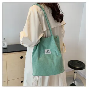 Elegante bolso de pana verde claro llevado al hombro en un entorno de estilo de vida.