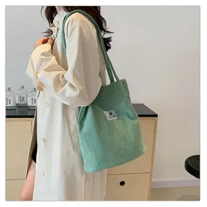 Vista lateral de una modelo con un bolso tote de pana verde menta en un ambiente minimalista.