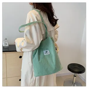 Vista trasera de una modelo con un bolso tote de pana verde claro en casa
