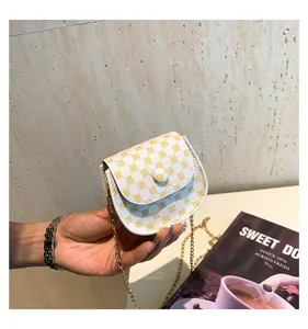 Primer plano de un elegante mini bolso bandolera con patrón de trébol amarillo en la mano