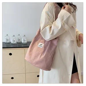 Primer plano de un bolso de pana rosa con un detalle de etiqueta tejida minimalista.