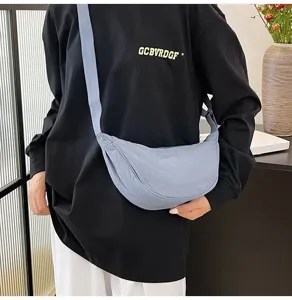 Detalle de un bolso bandolera de nailon azul llevado por una modelo con ropa informal.