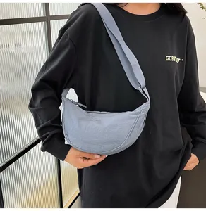 Vista detallada del bolso de media luna de nailon gris en un modelo que muestra su textura.