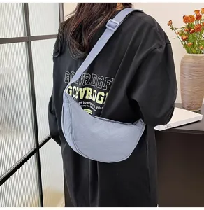 Bolso bandolera de nailon azul claro en forma de media luna llevado por una modelo