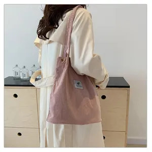Bolso de hombro de pana rosa combinado con una gabardina beige para un estilo casual.