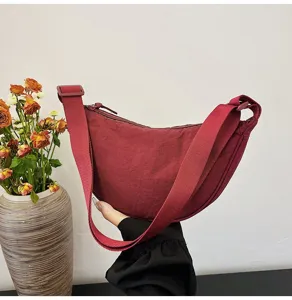 Vista detallada del bolso de nailon color burdeos con una correa ajustable para el hombro