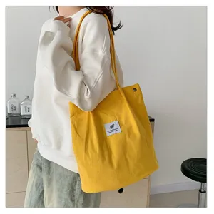 Vista lateral detallada de un bolso de pana amarillo con un parche de logo de hoja