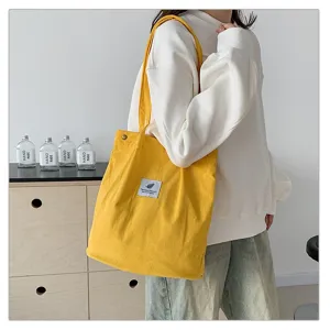 Vista detallada de un elegante bolso tote de pana amarillo llevado por una modelo