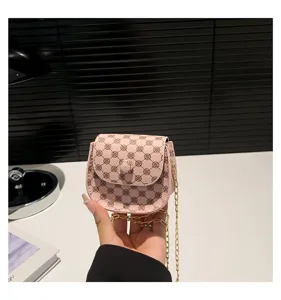 Primer plano de un mini bolso bandolera rosa con estampado de monograma y cadena dorada.
