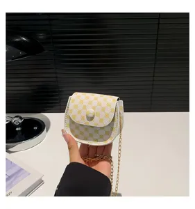 Primer plano de mini bolso bandolera con cadena y patrón de monograma amarillo en mano