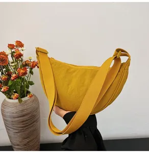 Detalle del bolso de hombro amarillo de nailon con correa ajustable y cierre de cremallera