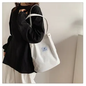 Primer plano de un bolso tote de pana blanco con un parche azul minimalista