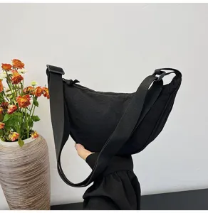 Vista lateral de un elegante bolso bandolera de media luna en nylon negro moderno