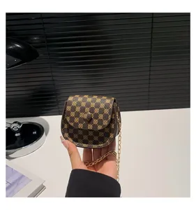 Detalle del patrón de monograma vintage y la cadena dorada en un mini bolso silla