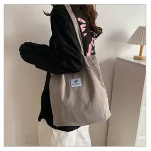 Bolso de hombro de pana gris de gran capacidad usado por una modelo en una habitación minimalista
