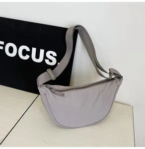 Primer plano de un bolso de media luna de nailon gris con correa