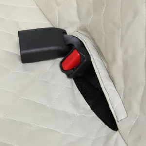 Detailed view of waterproof pet car seat cover seatbelt slot, beige quilted design.