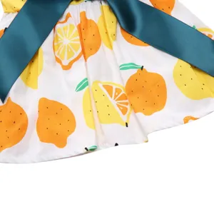 Close-up of lemon and orange fruit print on white fabric with teal satin ribbon
