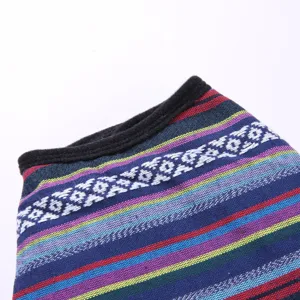 Dettaglio ravvicinato di un poncho a righe colorate per cani con ricamo geometrico