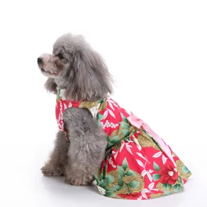 Side view detail of a grey toy poodle wearing a red floral printed pet dress with a pink bow.