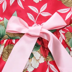 Macro detail of elegant pink satin bow on red floral print pet summer dress fabric