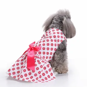Back view of a dog wearing a white summer dress with red daisies and a pink bow