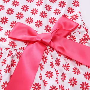 Detailed view of the elegant pink satin bow and vibrant red daisy floral print on a pet dress