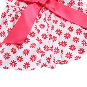 Detailed macro view showing pink satin bow and red daisy floral print on white dog dress