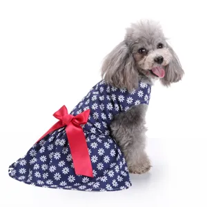 Close-up detail of a navy blue dog dress featuring white flower patterns and a large red silk bow