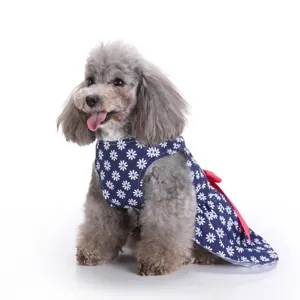Detailed view of a gray poodle wearing a navy blue daisy floral pet dress with red bow.