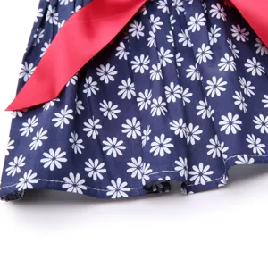 Close-up of cute navy blue pet dress with white daisy pattern and pink ribbon