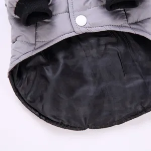Grey pet winter coat detail showing quilted fabric, black lining and snap button design.
