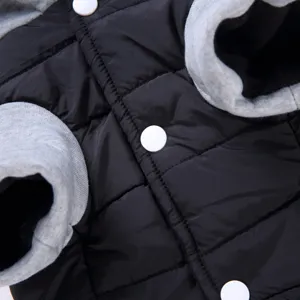 Close-up detail of pet winter coat featuring black quilted fabric, grey cuffs, and buttons.