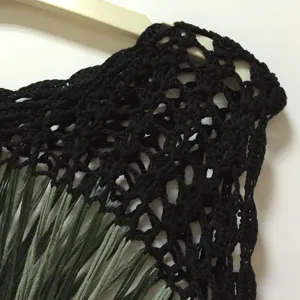Hand crocheted black sleeveless top detail, featuring green fringe and hollow out mesh design.