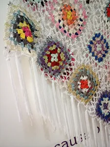 Detailed view of handmade crochet granny square cover-up with vibrant colorful floral patterns.