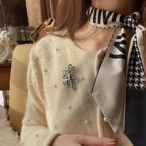 Detailed close-up of a circus clown brooch pinned on a beige pearl cardigan