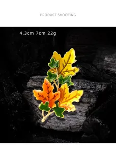 Vintage enamel maple leaf brooch with orange and yellow autumn leaves on dark charcoal.