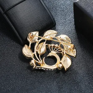 High-quality close-up of vintage golden matte peacock and leaf brooch with crystal accents