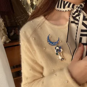 Close-up of a whimsical circus clown brooch with balloons and a blue crescent moon