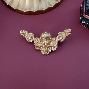 Makrodetail einer klassischen Putten-Reliefbrosche in elegantem, mattem Goldfinish