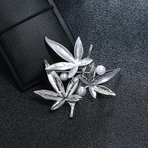 Close-up of a vintage silver maple leaf brooch featuring three white pearl accents