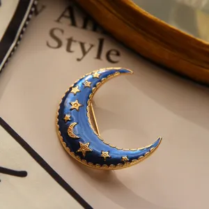 Detailed macro view of a vintage blue enamel crescent moon brooch with golden stars.
