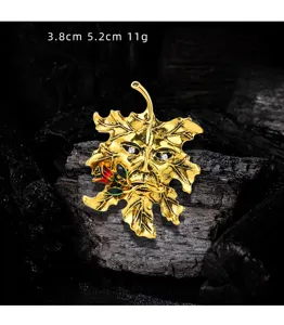 Detailed close-up of vintage golden maple leaf enamel brooch with tree man face design